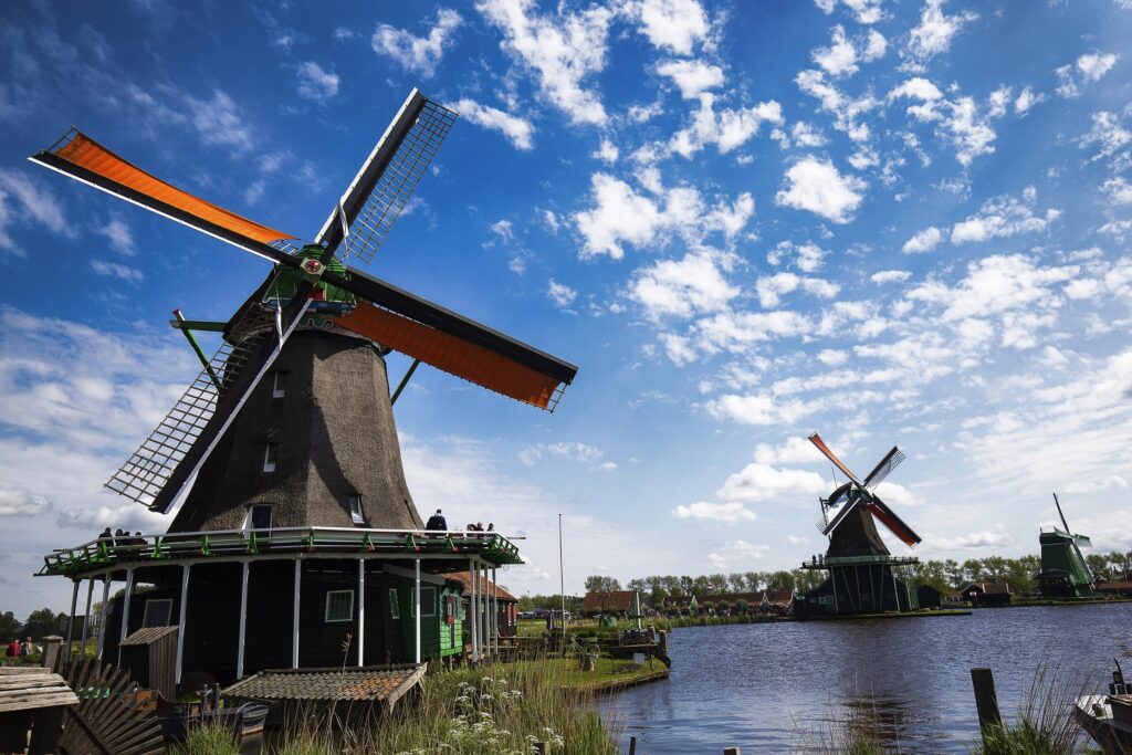 Low angle shot windmills zaanse schans neighborhood near lake netherlands — Holanda